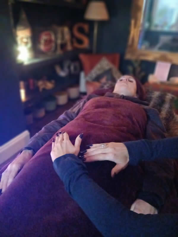 lady lying lengthways under red blanket with hands at forefront